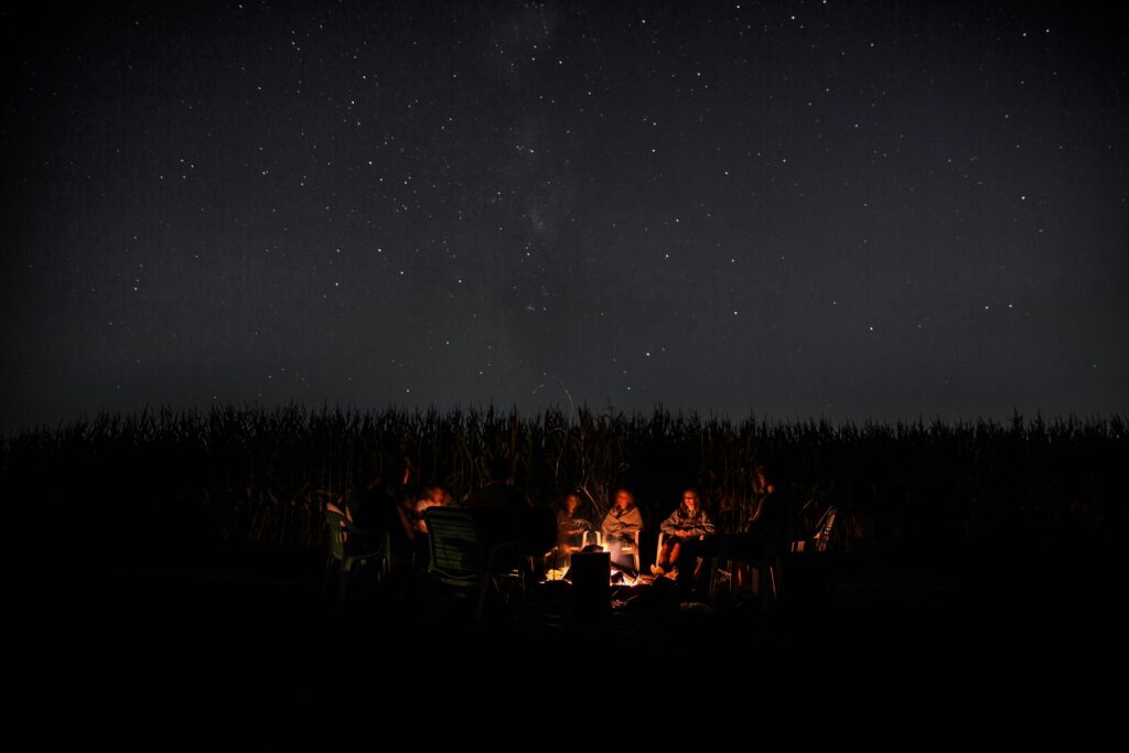 Groupe autour d’un feu de camp sous un ciel étoilé dans les Vosges